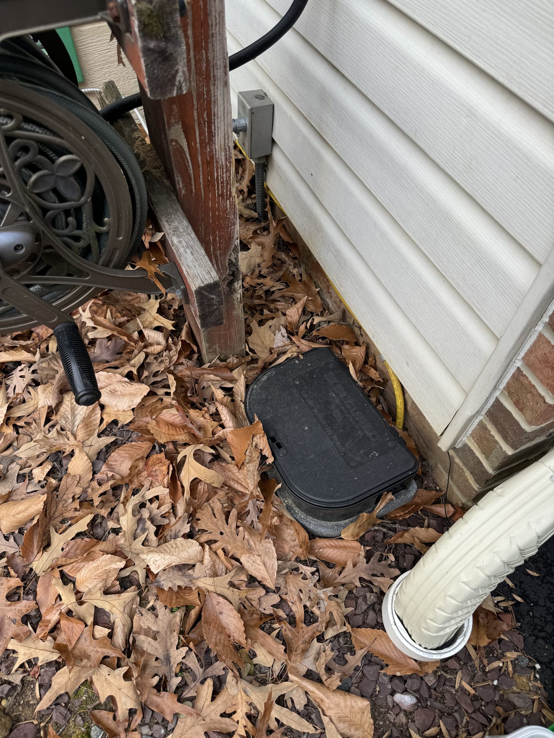 A rodent bait station placed at a home foundation entry point