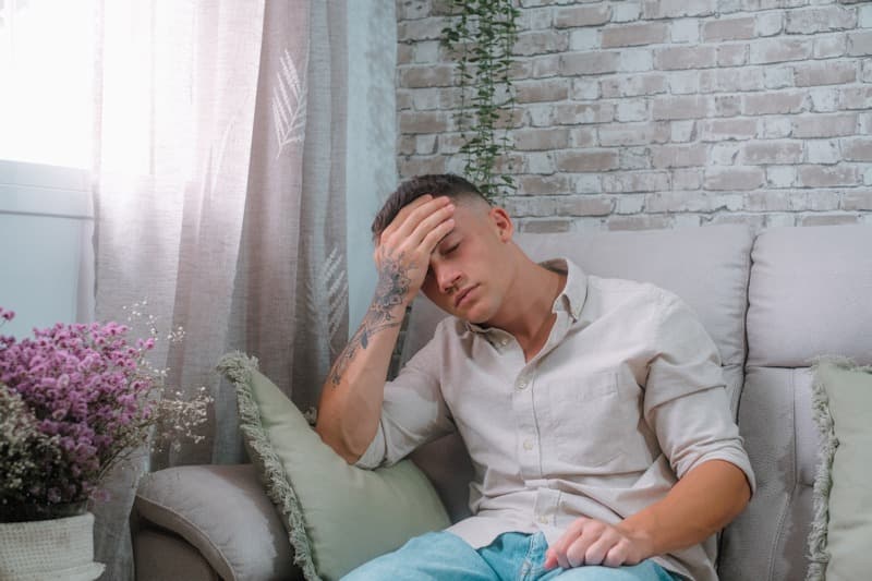 one-young-sick-man-sitting-on-the-sofa-feeling-bad after working in a crawl space
